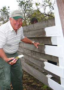 A man painting a wooden fence